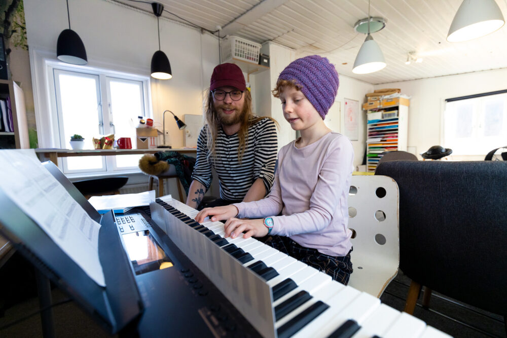 Lærer hjælper elev ved klaveret på Vanløse Friskole, hvor tryghed, musik og høj faglighed går hånd i hånd.